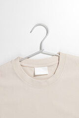 Beige t-shirt with blank label on a clothes rack. Ecology concept. Mockup.