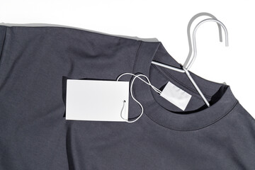 Gray t-shirt with blank clothing price tag or label mockup on a clothes rack. Ecology concept. Clothing sale concept
