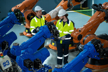 Engineer checking weld header of welding arm robot machine with data specification at industrial...