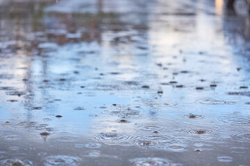 Heavy rain falling on the asphalt, puddles with splashes from drops..