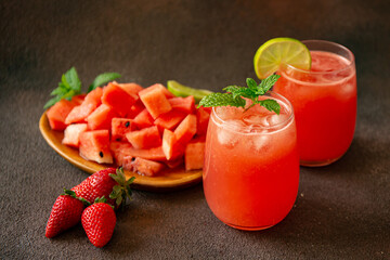 Pieces of watermelon on wood board and watermelon juice on dark brown background 