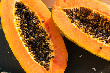 Two pieces of papaya on windowsill on a hot sunny day. Papaya cut in half.