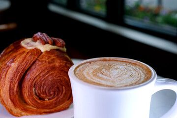 delicious dessert in a restaurant on a white plate round croissant with walnuts and custard puff pastry Vanilla Kouign Amann Round Croissant, New York Roll, Trendy Pastry cinnamon hazelnut latte