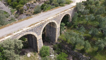 Fototapeta na wymiar Tatar Bridge - Very old stone arch bridge from Ottoman or even older times about 30 m long with three arches, 2 central piers, completely preserved near Urla, Turkish Aegean Sea