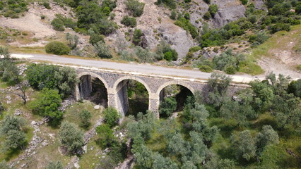 Fototapeta na wymiar Tatar Bridge - Very old stone arch bridge from Ottoman or even older times about 30 m long with three arches, 2 central piers, completely preserved near Urla, Turkish Aegean Sea