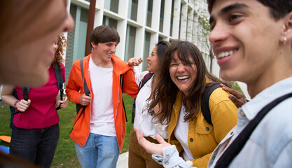 Group of multiracial young students having fun walking together on college campus. Happy teens hanging out outside of school. Generation z people laughing outdoors. Scholarship concept
