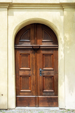 Red wood door with an arch against a yellow stone wall. From the door of the world series.