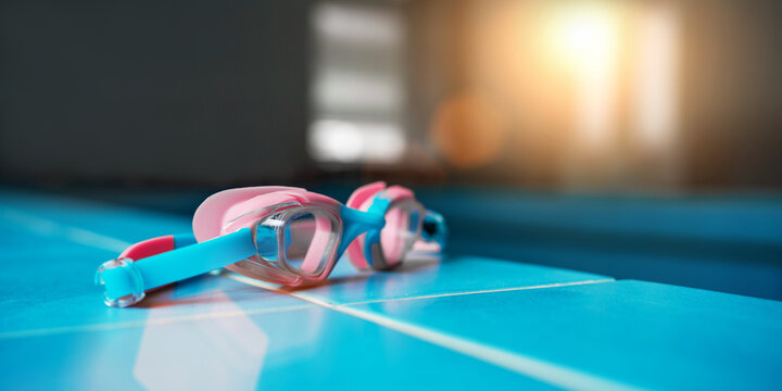 Swimming protection goggles lies on blue tiled pool edge close side view. Swimming training concept.