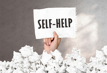 Hand holds a piece of paper with text Self Help on a gray wall background
