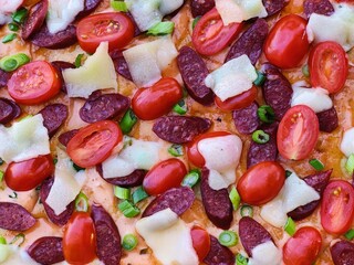 pepperoni pizza with sausage and tomatoes, close-up 