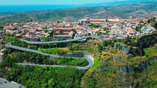 Aerial view of a serpentine road with an Italian old town in the background. Gerace old village in Calabria region in Italy.