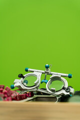 Close-up trial frame glasses and set of lenses on green background. Trial frame glasses to examine eye visual system of patient with short or long power vision.