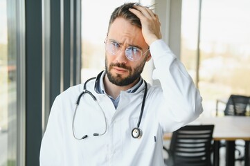 Stressed male doctor. Mid adult male doctor working long hours. Overworked doctor in his office....