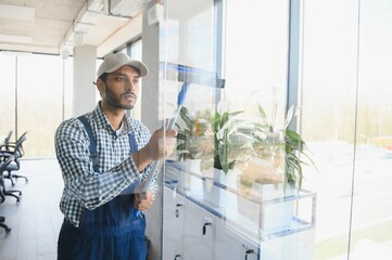 Male janitor cleaning window in office