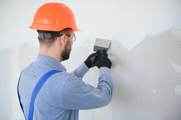 man drywall worker or plasterer sanding and smoothing a plasterboard walls with stucco using a...