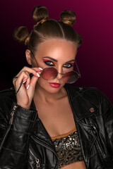 Portrait of a young sassy girl with blond hair in the studio on a pink background.