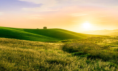 beautiful sunset or sunrise in rural countryside green hills with farm and mountains on background
