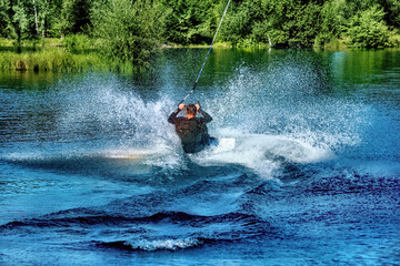 A man wakeboarding on a lake on summer day in a life  jacket. Soft focus. Action blur.