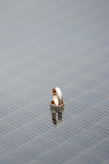 Two wedding rings in yellow and white gold. Wedding rings on the glass surface lie on top of each other. A symbol of loyalty. Gold Wedding Rings