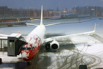 Airplane before flight. Winter night at airport during snowfall