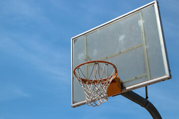 Naklejka premium Outdoor neighborhood basketball court park and recreational area, Basketball net and backboard against sunny blue sky with copy space