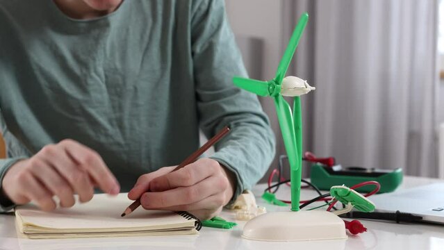 Closeup view of a Caucasian student working on the science project about wind energy.