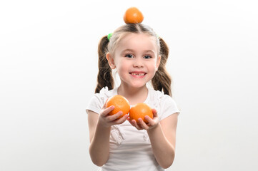 Portrait of a small beautiful girl on a white background with tangerines in her hands.