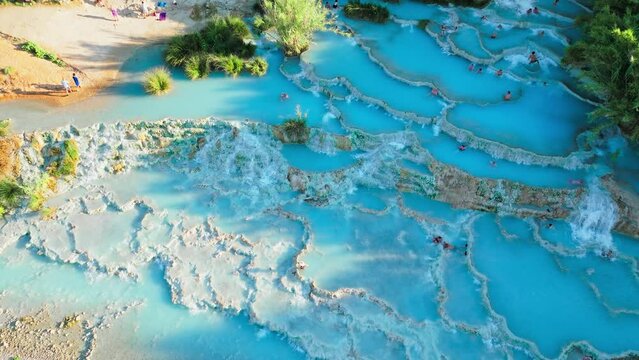 Aerial view of beautiful sunrise over Saturnia thermal baths in Italy. People enjoy Saturnia thermal hot springs of silk blue water pools heated by the nearby volcano in Tuscany.