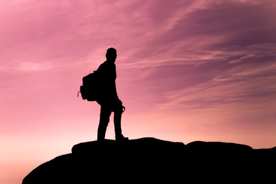 Silhouette of hiker adventurer against a purple sunset sky