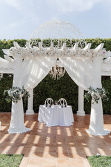wedding arch for an outdoor wedding ceremony on a green lawn, decorated with white flowers