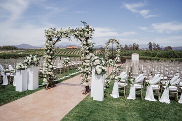 wedding arch for an outdoor wedding ceremony on a green lawn, decorated with white flowers