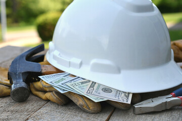 Hard hat with construction tools and cash money - concept for building cost or fraud, scam, bribes 