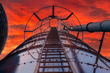 Looking up a silo ladder with bright orange sky
