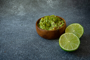 Toasts with fresh  Mexican guacamole and lime on wooden board on dark background 