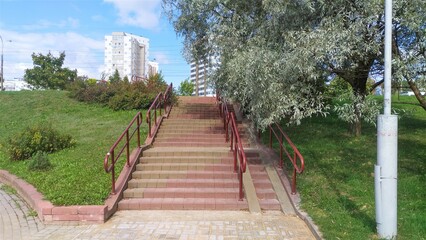 At the exit of the park to the city street there is a staircase with a metal handrail. It can also be used by people with disabilities. There are grass, bushes and trees around it