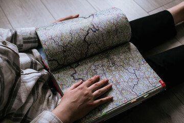 A close-up of a girl's hand lying on a book map of Europe's routes - 601523870