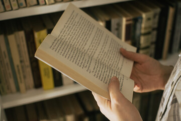 Open old book held against a bookshelf - 601523871