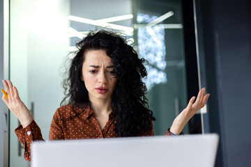 Upset and nervous business woman looking at laptop screen, female worker working inside office...