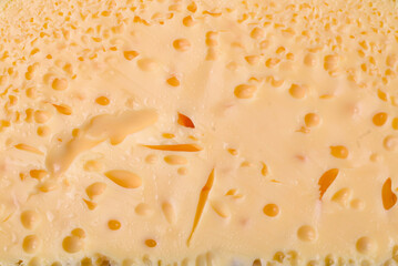 Delicious porous yellow cheese cut in large pieces on a ceramic plate
