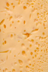 Delicious porous yellow cheese cut in large pieces on a ceramic plate