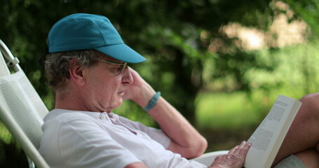 Senior person reading book outside at park