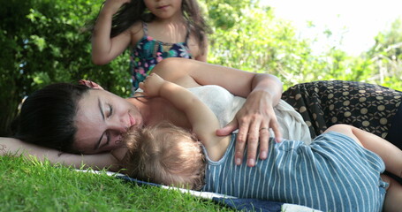 Mother with baby and daughter outside in nature. Authentic real life mom with children outdoors