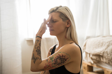 Albino calm woman practicing breathing yoga pranayama while sitting at the floor indoors