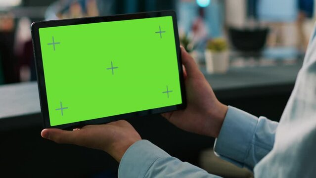 Boutique worker analyzing digital device with chroma key green screen mock up display, working in clothing store. Asian worker holding tablet computer in shopping mall. Technology concept