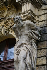 Fototapeta na wymiar Klasyczny posąg umięśnionego mężczyzny dźwigającego coś na plecach, element architektury budynku w mieście