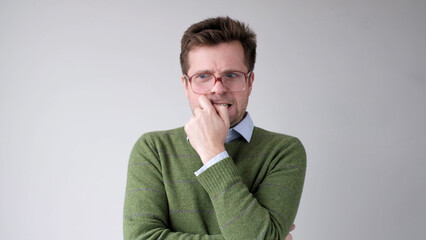 A European young man is nervous and biting his nails.