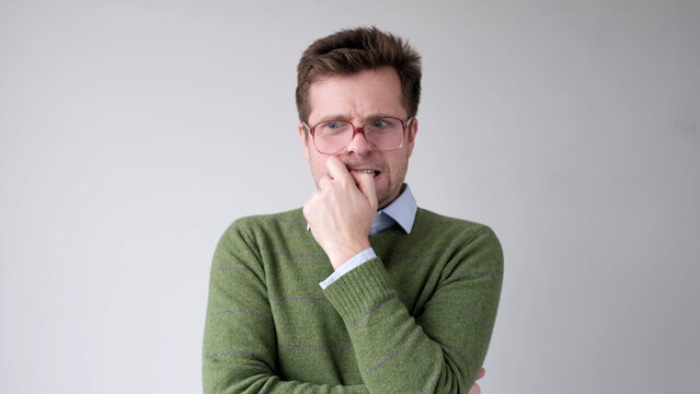 A European young man is nervous and biting his nails.