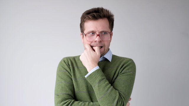 A European young man is nervous and biting his nails.