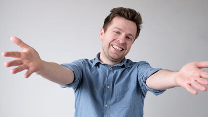 European young man is reaching out his hands forward to embrace the interlocutor, greeting him