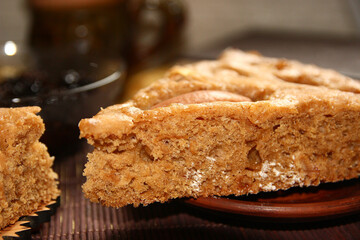 Homemade apple pie, tea, wooden necklace and jam from cones on the table.